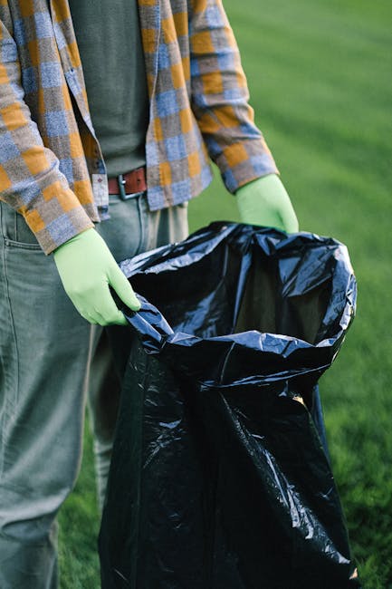 A disorganized pile of discarded waste materials positioned against an exterior wall on a paved surface. The pile includes wooden objects such as a ladder and slatted frames, some of which appear weat